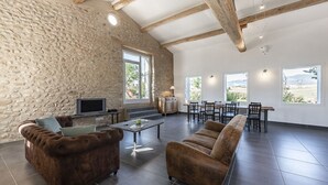 A spacious living room with stone walls, a fireplace, a television, and a dining area with natural light from large windows. - Loft in Provence in Moustiers Sainte Marie and near the Sainte Croix Lake (Moustiers-Sainte-Marie)