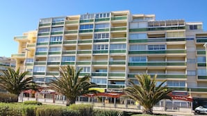 Ein mehrstöckiges Hotel mit Balkonen, einem Restaurant und einer Lage direkt am Strand.