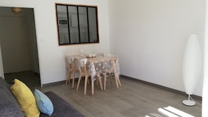 Una habitación con una mesa de comedor y sillas, una lámpara blanca y un ventanal grande.