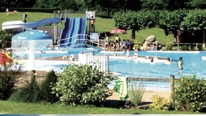 Ein Schwimmbecken mit Wasserrutsche und Rettungsschwimmerstation.