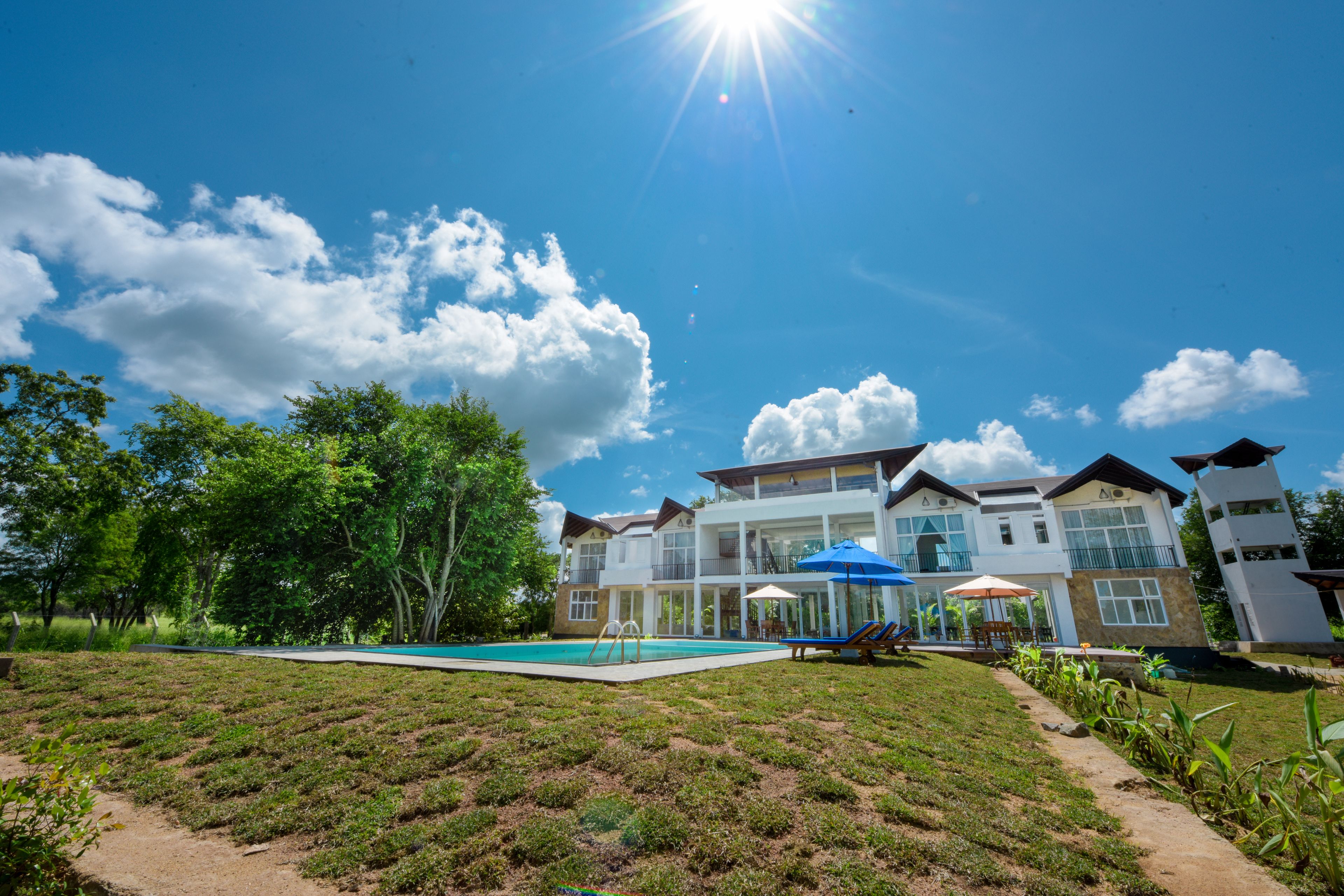 A large house with a swimming pool, outdoor furniture, and a clear blue sky.