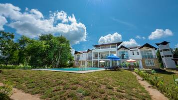 A large house with a swimming pool, outdoor furniture, and a clear blue sky.