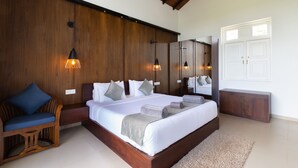 A bedroom with a large bed, wooden headboard, two pendant lights, a wooden bench, a large mirror, and a white wardrobe. - Subaseth Villa (Nuwaragam Palatha Central)