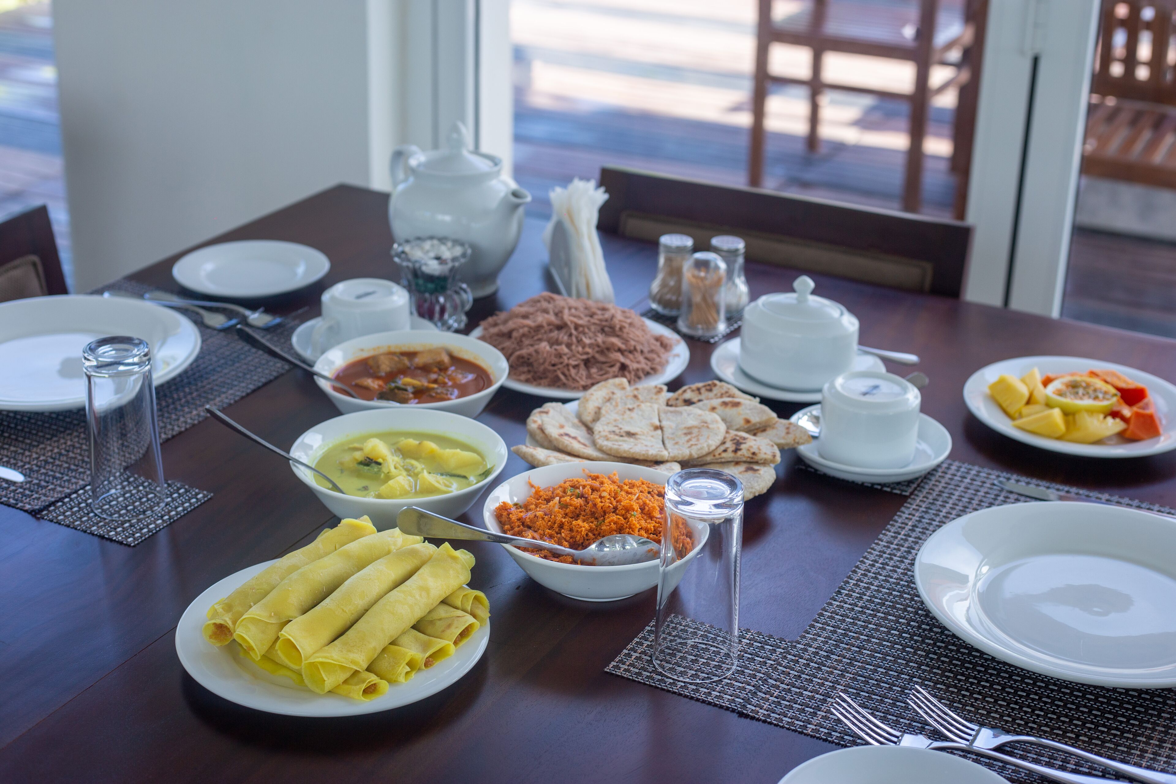 A dining table set with various dishes, including bowls of soup, plates of food, and a teapot.