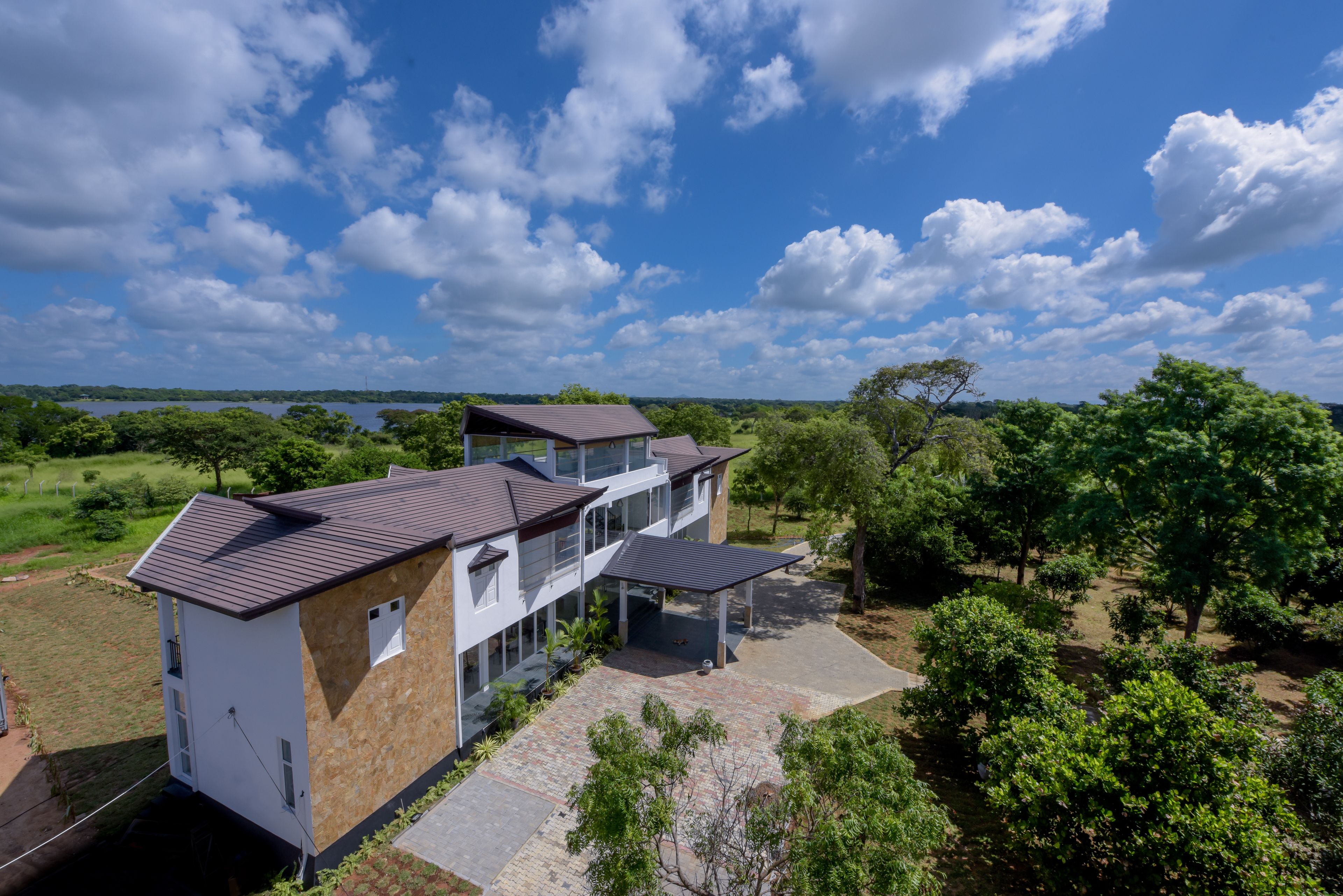 A modern two-story house with a flat roof, large windows, and a covered patio area.