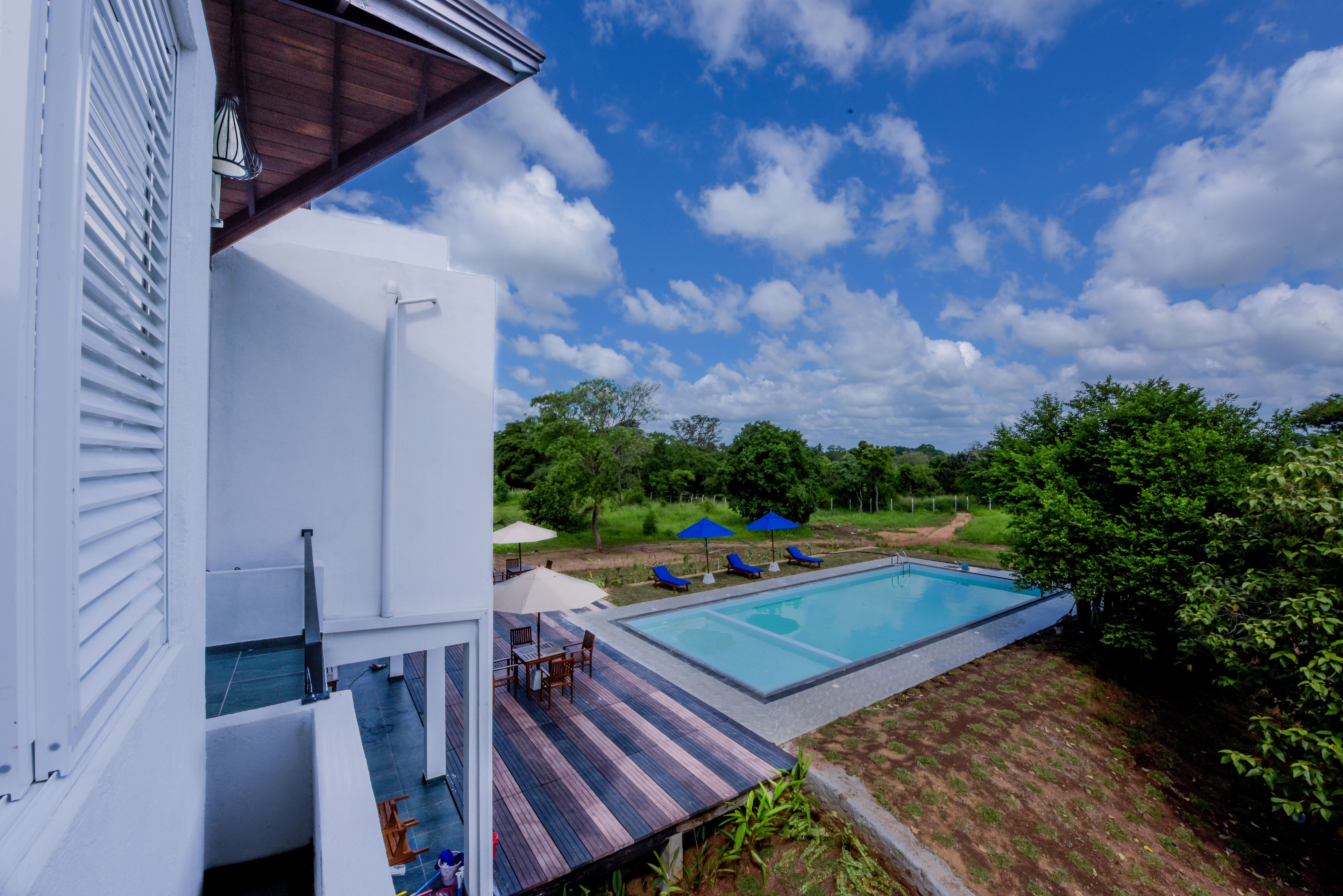 A modern house with a swimming pool, outdoor furniture, and a view of the surrounding greenery.