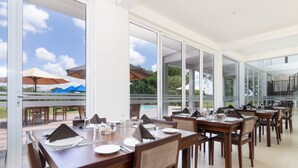 A dining area with tables set for a meal, large windows, and a view of the outdoors. - Subaseth Villa (Nuwaragam Palatha Central)