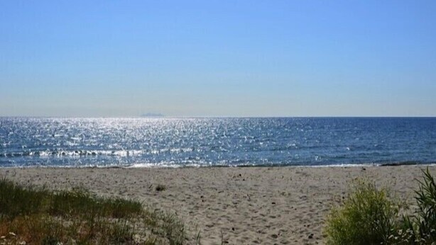 Una playa con cielo despejado y mar tranquilo.