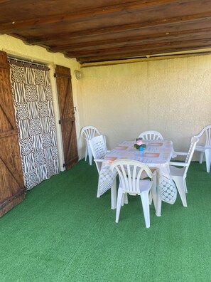 Une terrasse extérieure avec une table et des chaises, un rideau à motifs et un plafond en bois.