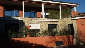 A modern building with a stone facade, large windows, and a balcony with potted plants. - Nice air-conditioned 3rooms 3***in ground floor, private terrace , swimming pool (Saint-Raphaël)