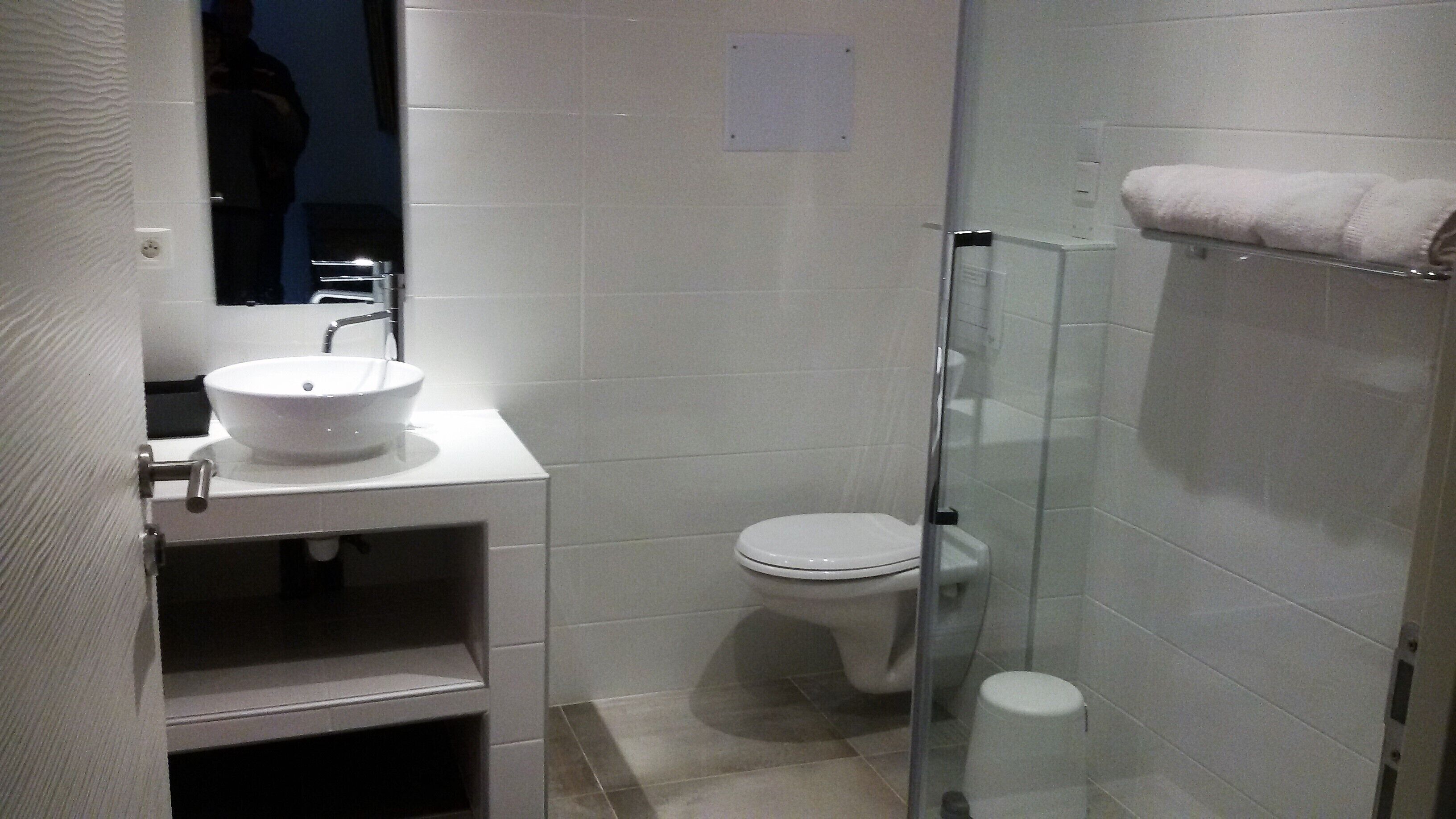 A bathroom with a white sink, toilet, and glass shower enclosure.