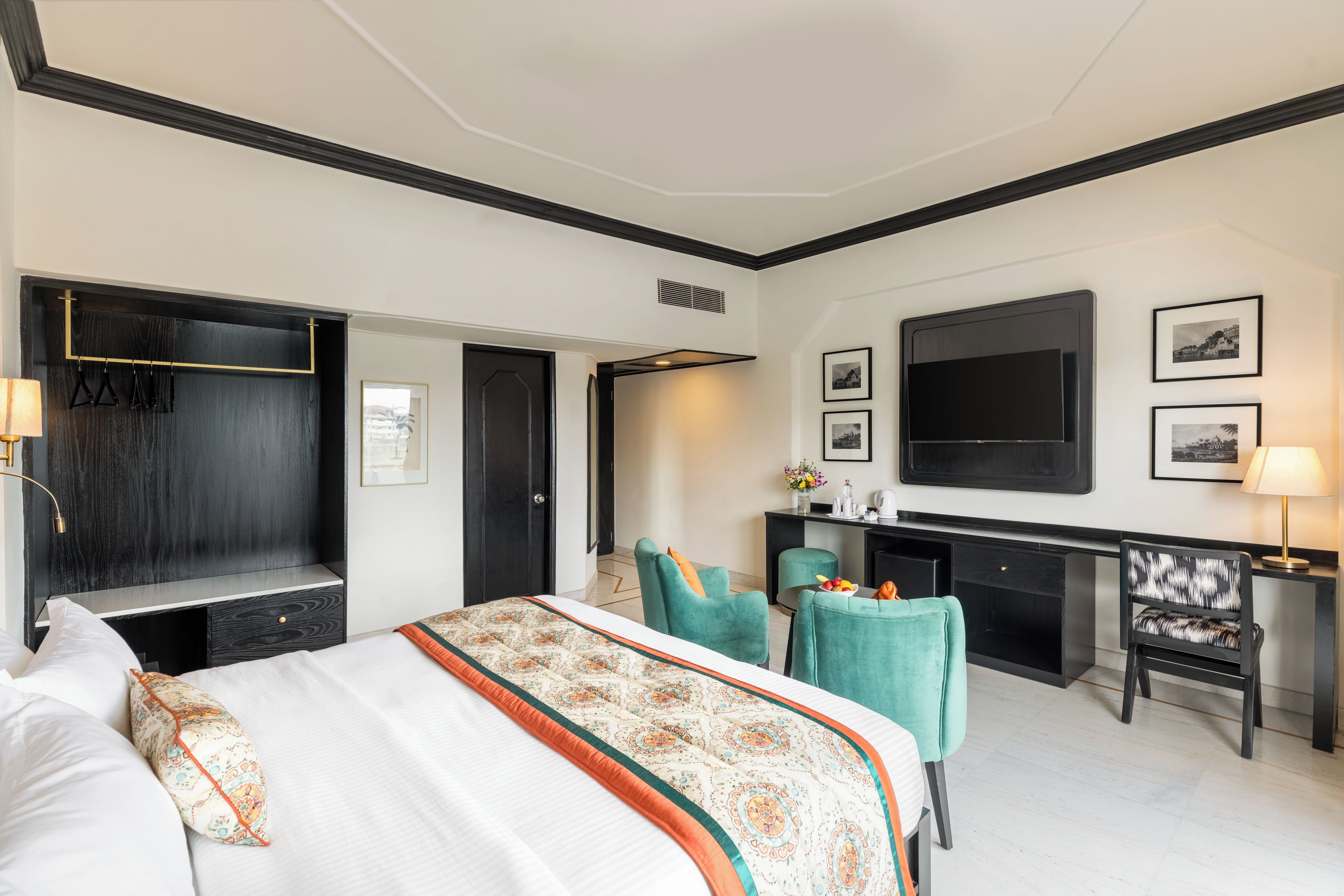 A hotel room with a bed, a desk, two chairs, a TV, and a wardrobe.