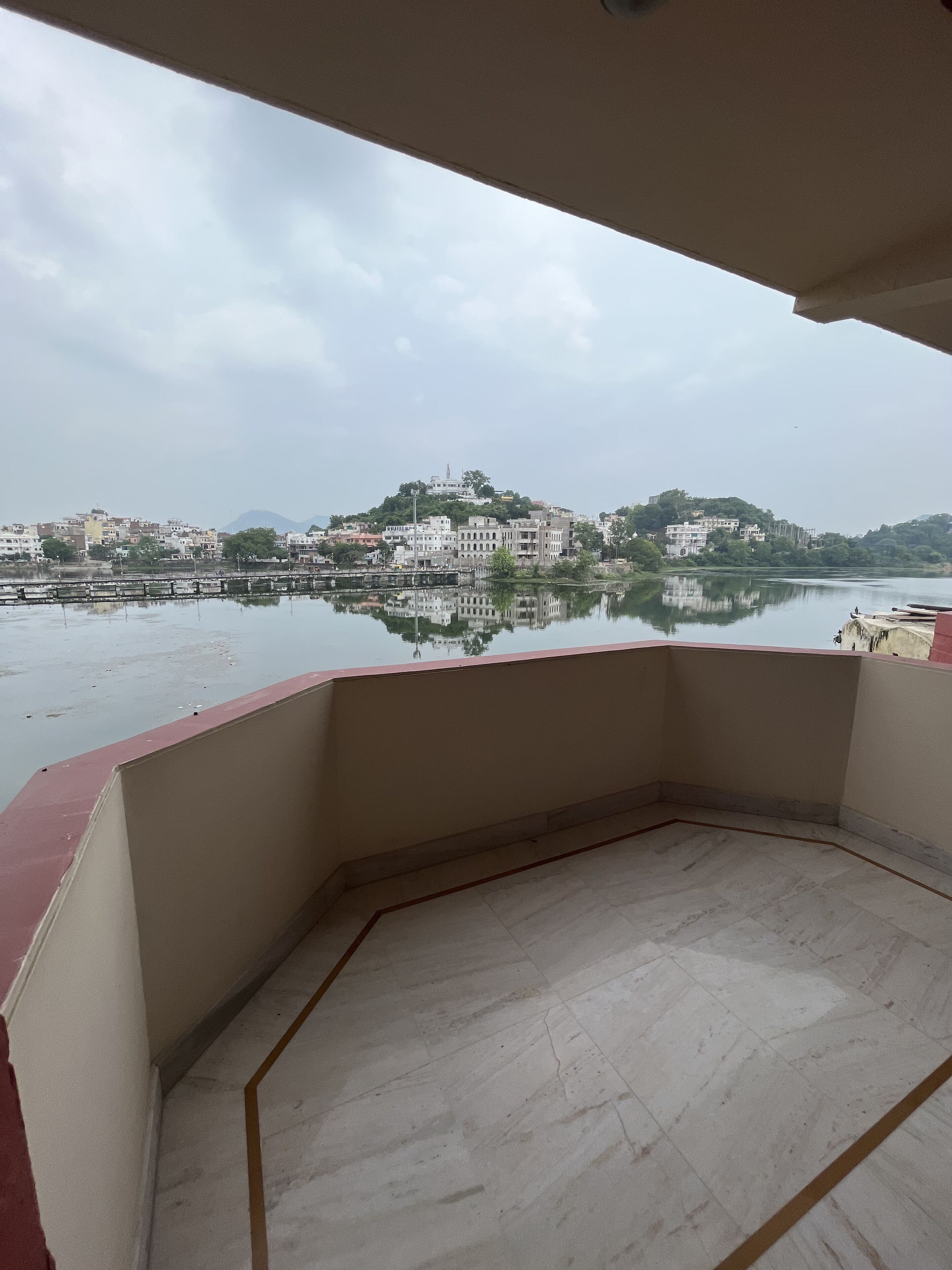 A balcony with a view of a river and buildings across it.