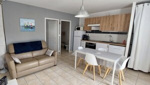 Un espace de vie compact comprenant un canapé, une table à manger et un coin cuisine.