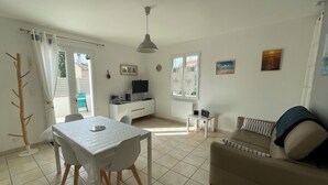 Un salon comprenant une table à manger, un canapé et un téléviseur posé sur un meuble.