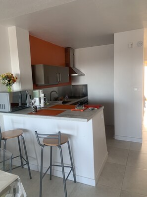 A modern kitchen with a central island, stainless steel appliances, and bar stools.