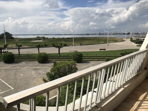 A parking lot with a view of a body of water and distant buildings.