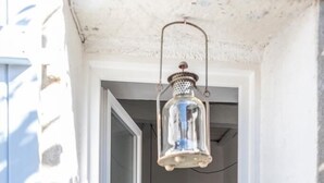 A window with a hanging lantern, a small window sill with two pots, and a stone on the right. - The village candy (Meria)