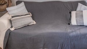 A room with a grey sofa, a white door, and a lamp with hats. - The village candy (Meria)