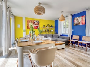 Uma sala de jantar com mesa de madeira, cadeiras e um sofá.