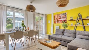 A modern living room with a sofa, dining table, chairs, and a coffee table.