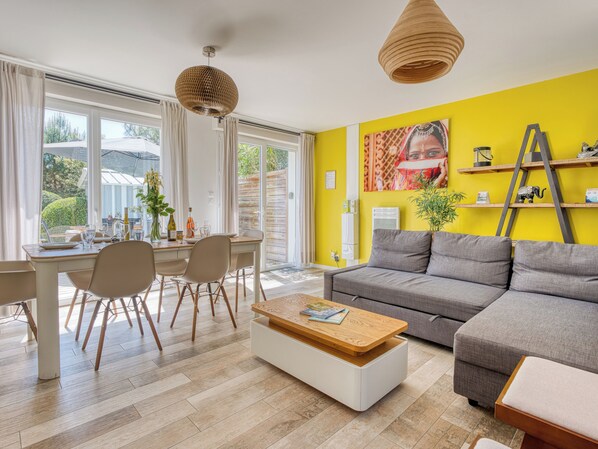 A modern living room with a sofa, dining table, chairs, and a coffee table.
