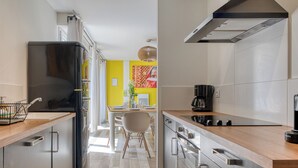 A modern kitchen with stainless steel appliances, a wooden countertop, and a view into a dining area.