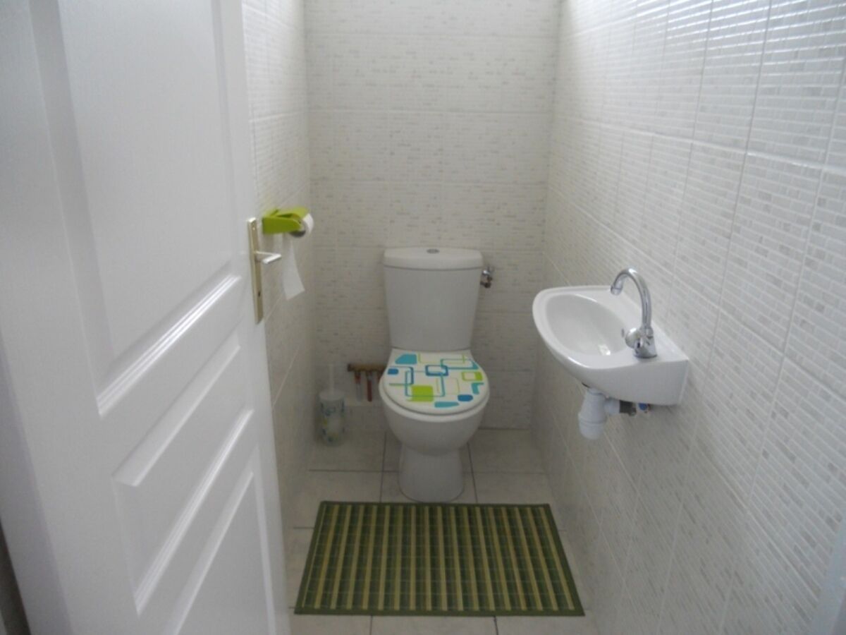 A small bathroom with a toilet, sink, and a green mat.