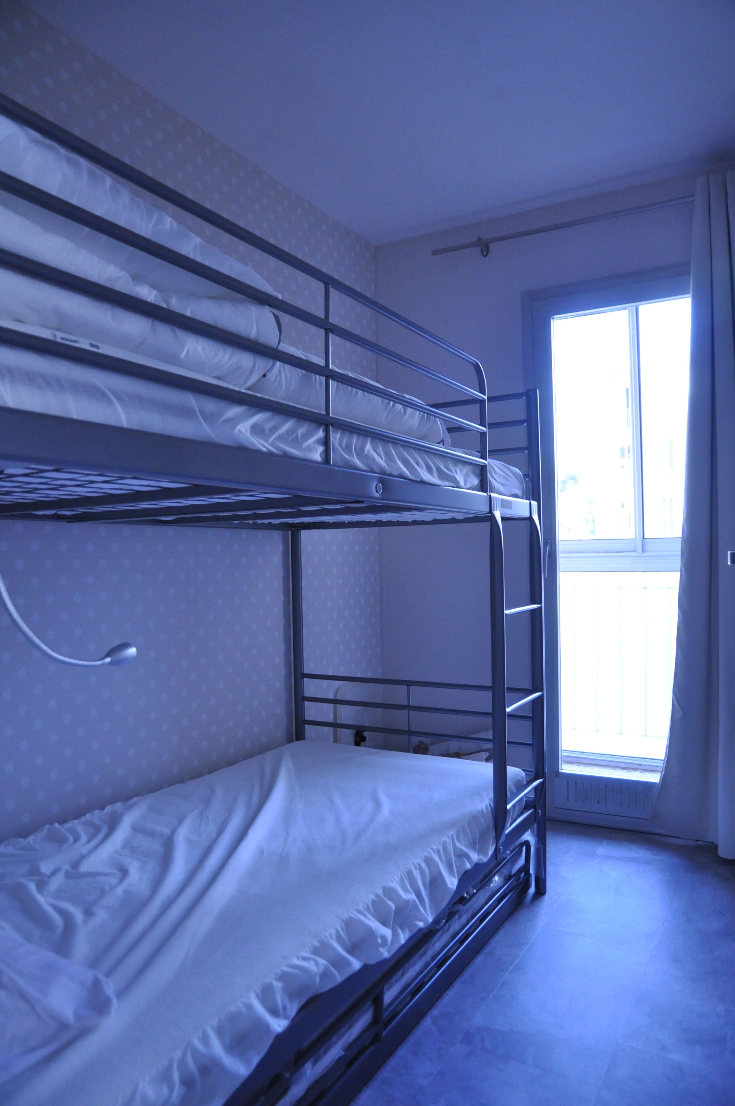 A bunk bed room with a window and a door.