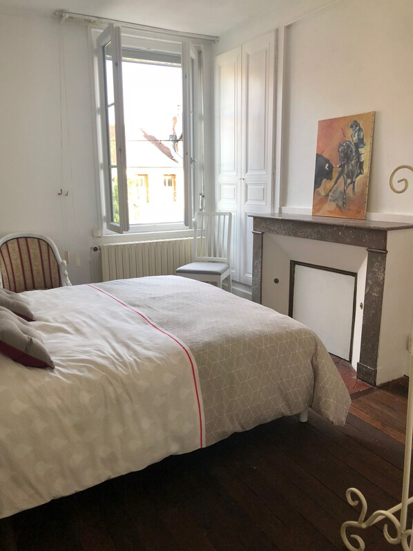 Un dormitorio con una cama, una silla, una chimenea y un ventanal.