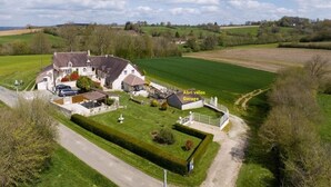 Een groot huis met garage, omgeven door groene velden en een heldere lucht.