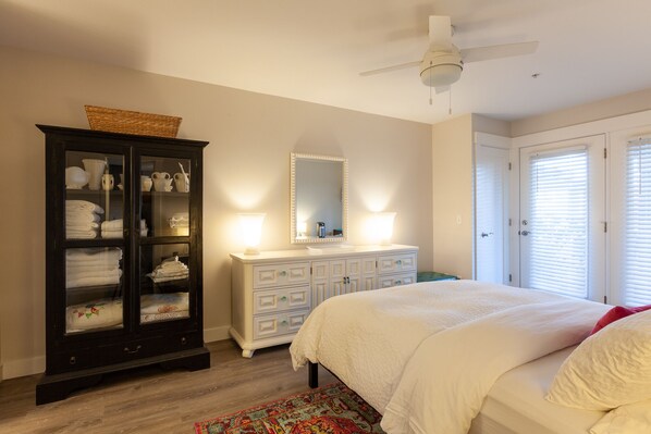 A bedroom with a bed, dresser, and a cabinet with towels.
