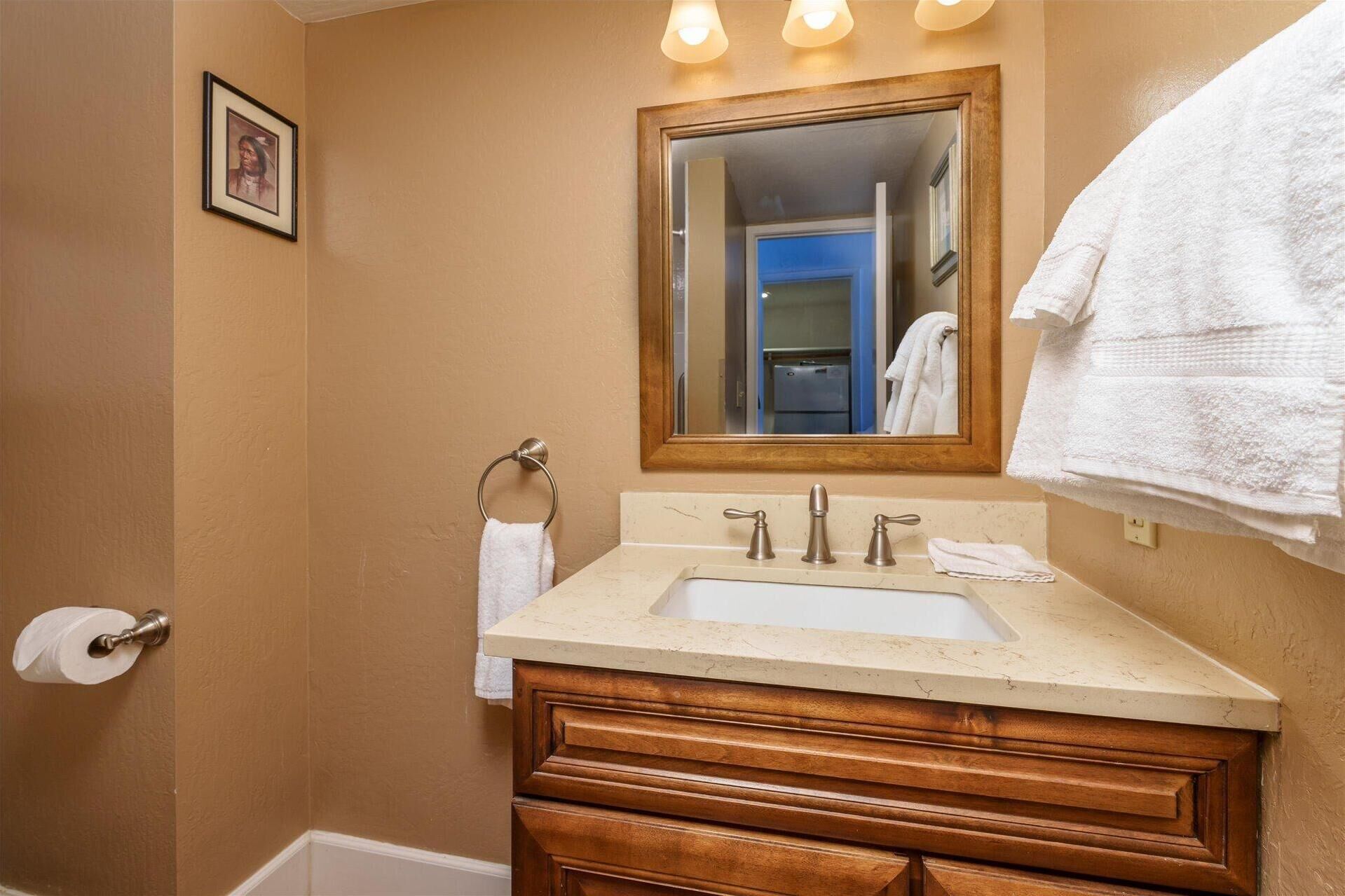 A bathroom with a wooden vanity, a sink, a mirror, and a towel rack.