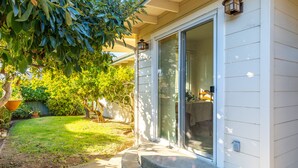 A house with a front porch, a sliding glass door, and a small garden with a lawn and potted plants. - Beach House Perfect for your Next Getaway! (Morro Bay)