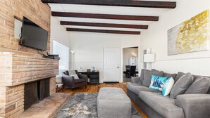 A living room with a fireplace, a gray sofa, and a large painting on the wall. - Beach House Perfect for your Next Getaway! (Morro Bay)