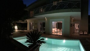 A modern house with a swimming pool, outdoor seating, and a balcony.