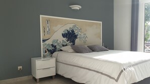 A bedroom with a bed, nightstand, and a wall-mounted artwork.