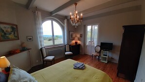 Un dormitorio con una cama grande, dos sillas, un televisor y una araña.