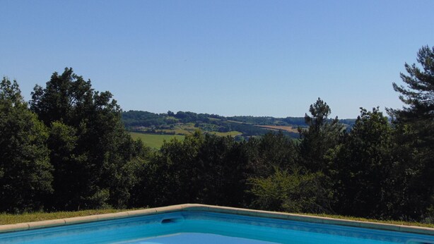 Una piscina con vistas a un paisaje montañoso y árboles.