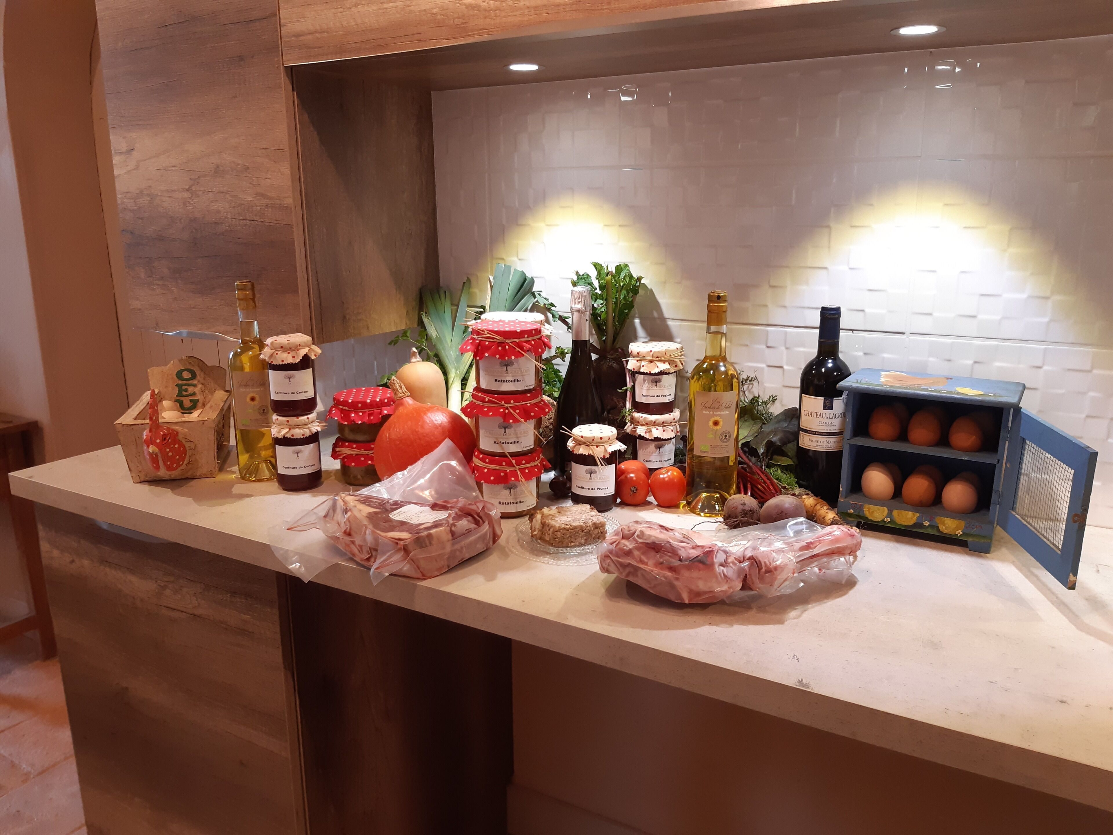 A kitchen counter with various food items, including jars of preserves, bottles of wine, and packaged meats.