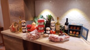 Una encimera de cocina con diversos alimentos, como tarros de conservas, botellas de vino y embutidos envasados.
