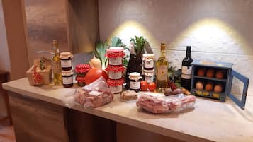 A kitchen counter with various food items, including jars of preserves, bottles of wine, and packaged meats.