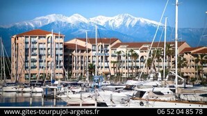 A marina with boats and a hotel with a mountain backdrop.
