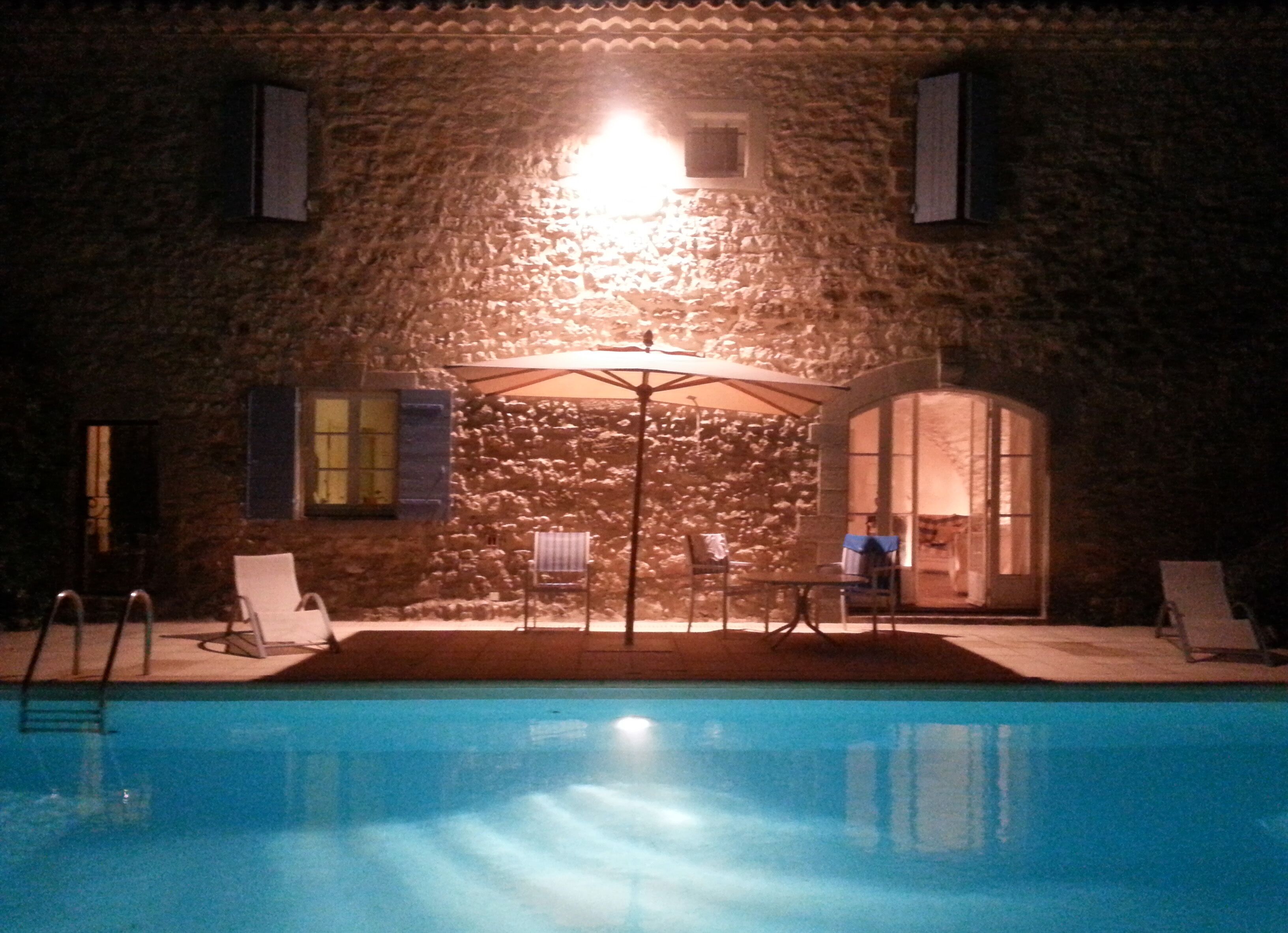 Un bâtiment en pierre doté d’une piscine, d’un espace extérieur aménagé et d’un éclairage puissant.