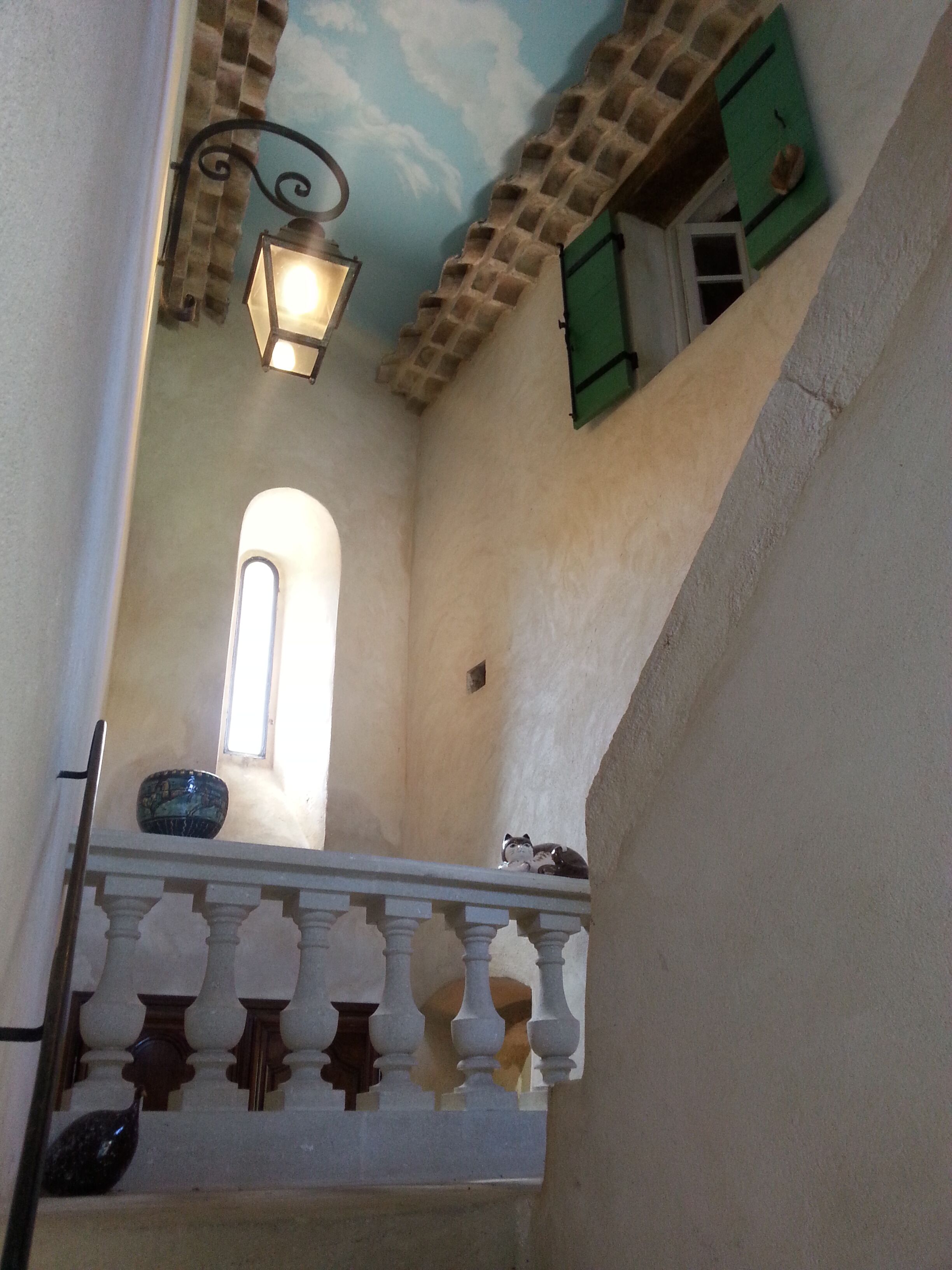 A narrow corridor with a balcony, a small window, and a decorative ceiling.