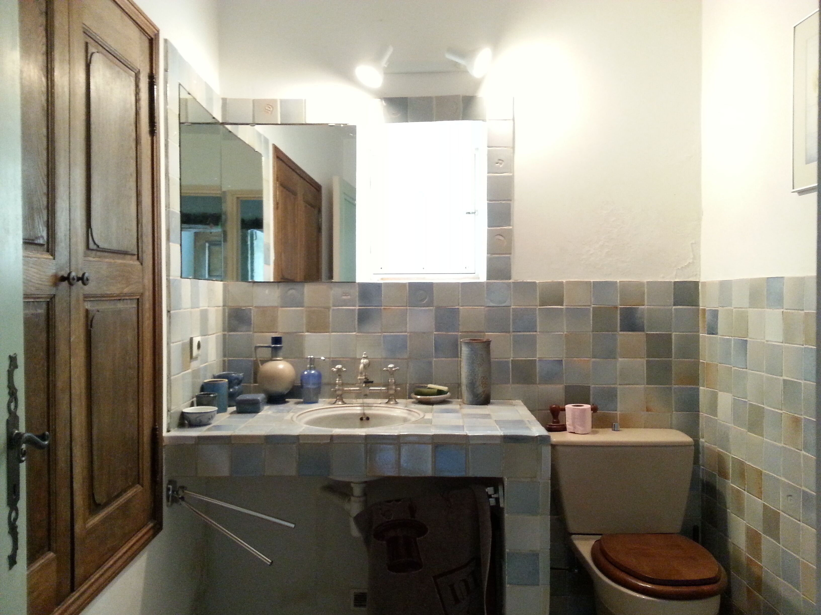 Un bany amb una porta de fusta, un lavabo amb un mirall a sobre i un vàter.