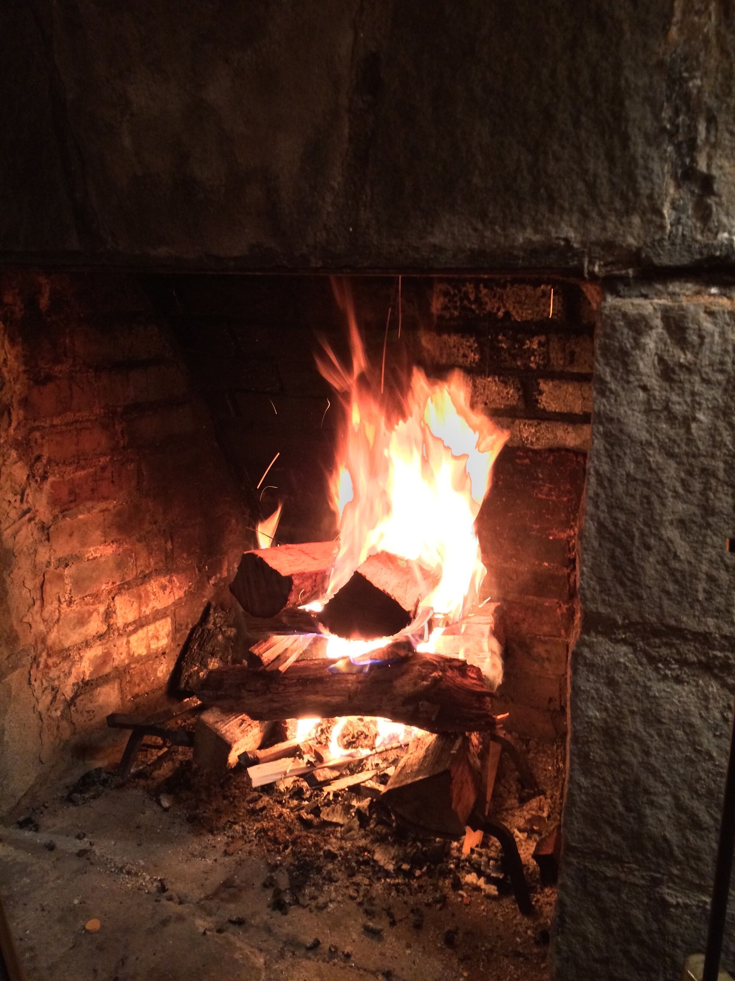A fireplace with burning logs and visible sparks.