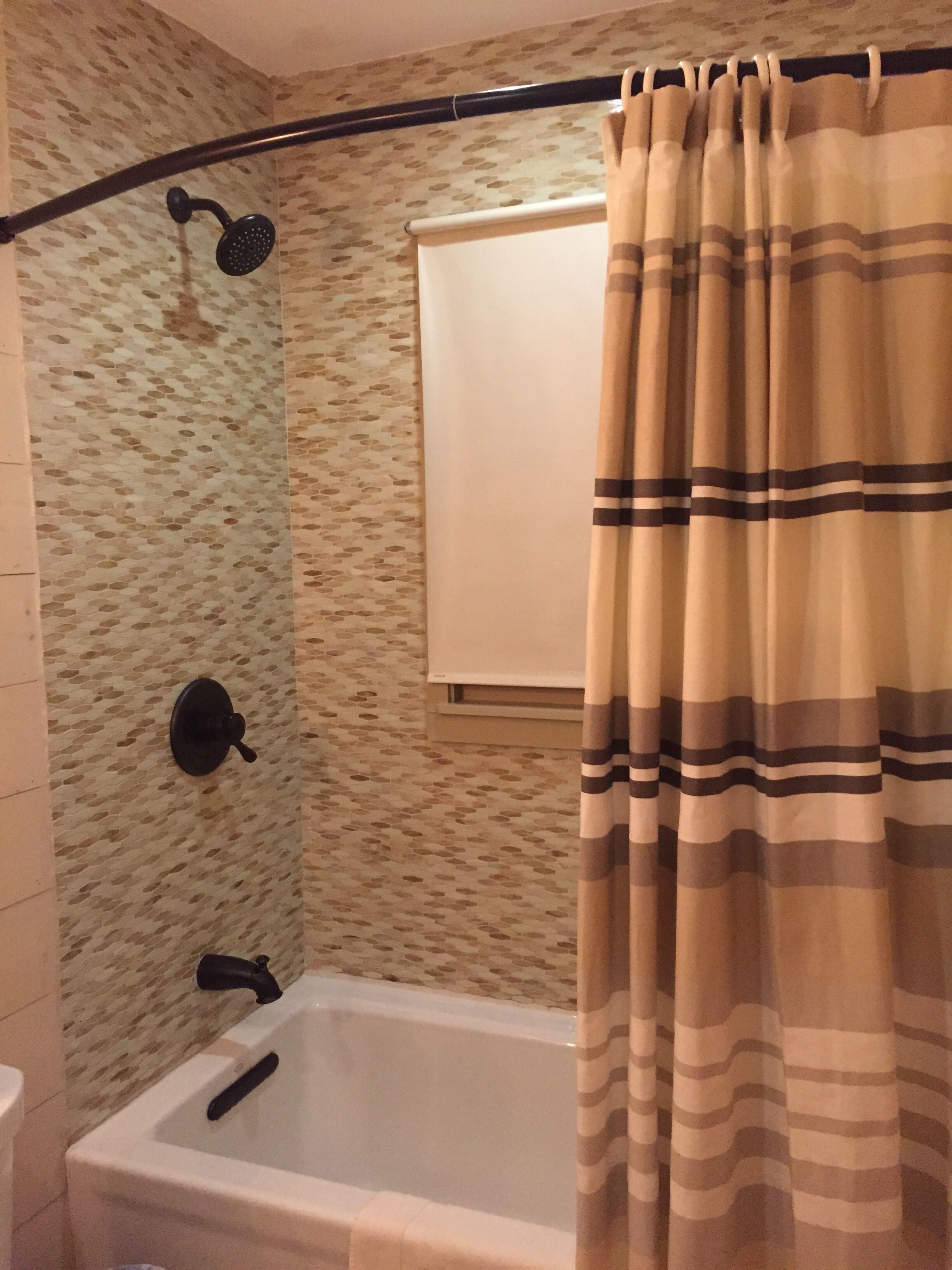 Une salle de bain avec une baignoire, une douche et un rideau.