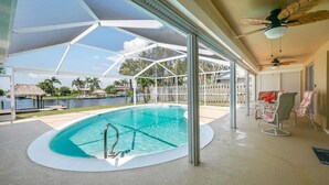 Et overdækket udendørs swimmingpool med frit udsyn til det omkringliggende område, herunder et hegn og palmer.