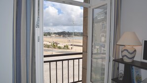 A room with a view of a beach, a lamp on a shelf, and a window with curtains. - F2 Sea and Morgat beach view with small balcony (Crozon)